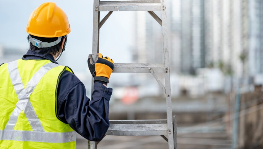 A construction worker standing next to a ladder
